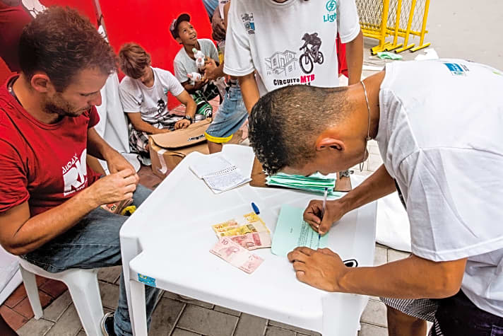   Rennchef Thiago Gomes (rotes Shirt) bringt nicht nur Stimmung, sondern auch Geld in die Fevelas.