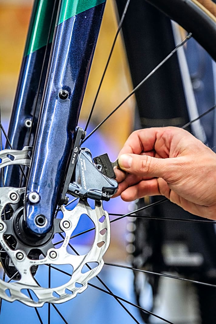 Verölte Beläge lassen Rennrad-Scheibenbremsen quietschen, sie müssen ausgetauscht werden: ­Sicherungssplint und Schraube entfernen – dann können die Beläge einfach nach oben herausgenommen werden. 